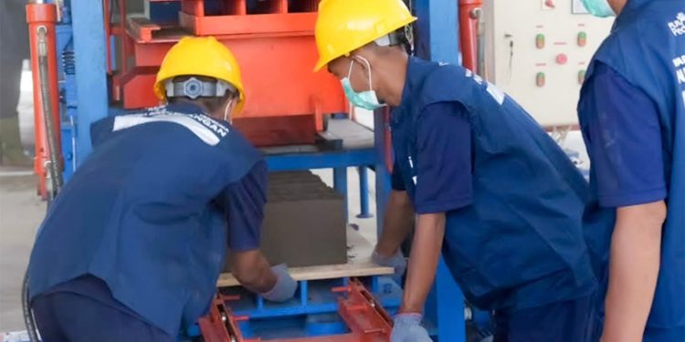 Ilustrasi warga binaan sedang melakukan pengolahan FABA menjadi batako. Melalui mesin _press_ berkapasitas tinggi, proses ini mampu menghasilkan hingga 1 juta batako setiap tahun.