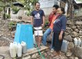 Kepala Desa Leuwayan Emanuel Ledo bersama Sophia Tuto dan pendamping dari Plan Indonesia menunjukkan tugu kran yang dibangun atas intervensi Plan Indonesia di desa tersebut, Rabu, 12 November 2025.