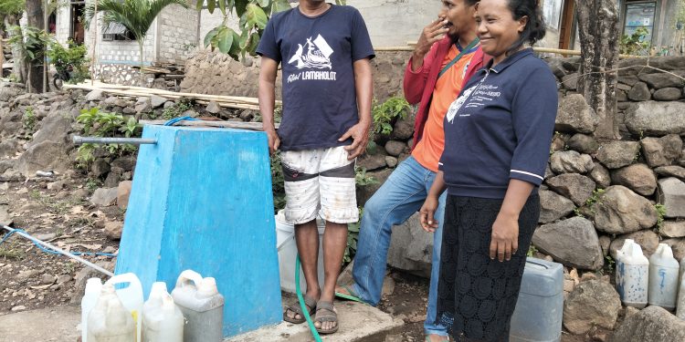 Kepala Desa Leuwayan Emanuel Ledo bersama Sophia Tuto dan pendamping dari Plan Indonesia menunjukkan tugu kran yang dibangun atas intervensi Plan Indonesia di desa tersebut, Rabu, 12 November 2025.