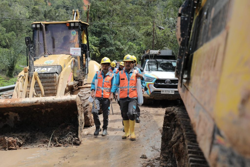 Tampak petugas PLN menyusuri jalur berlumpur menuju titik terdampak di Adian Koting, Tapanuli Utara.